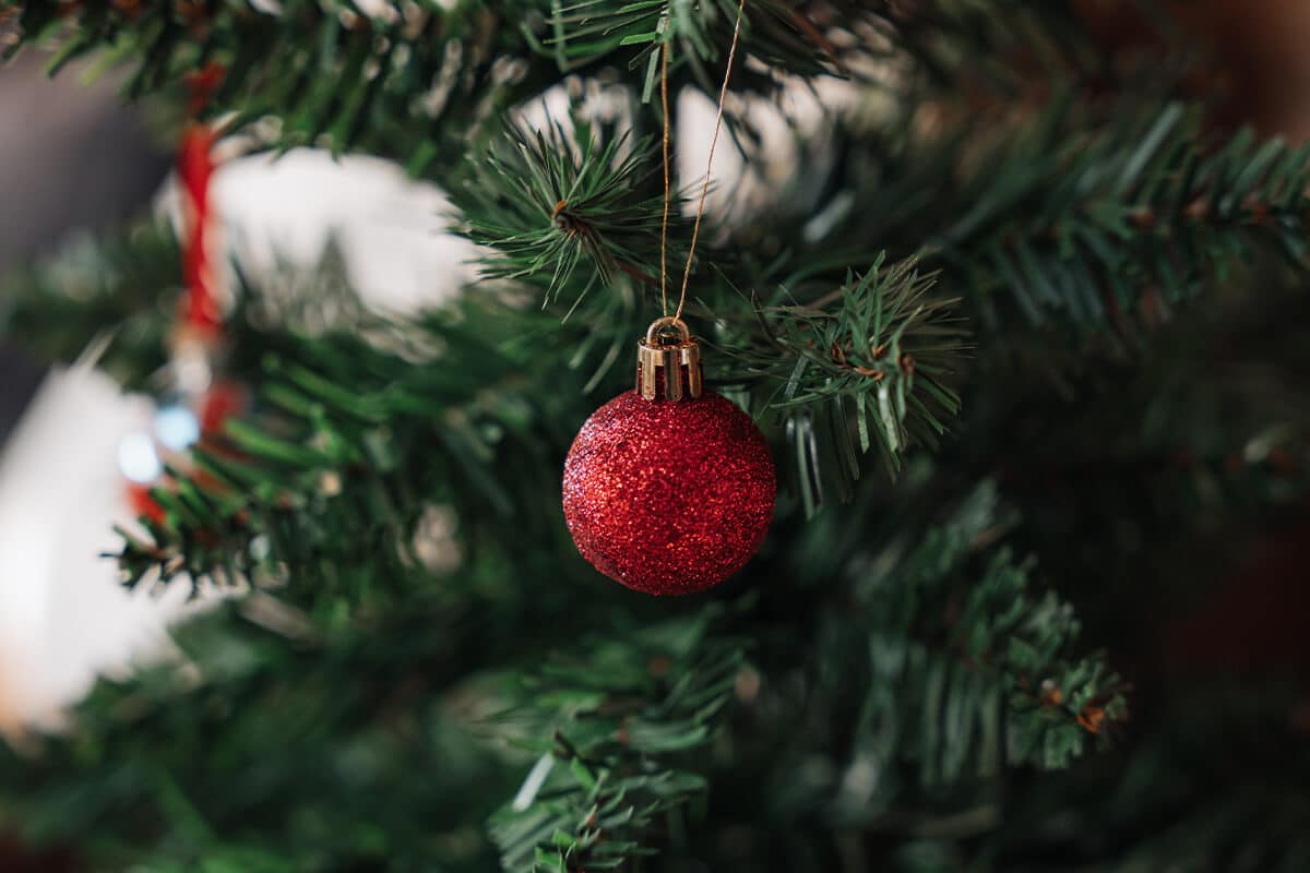 Weihnachtsbaum mit roter Weihnachtskugel auf Glitzer