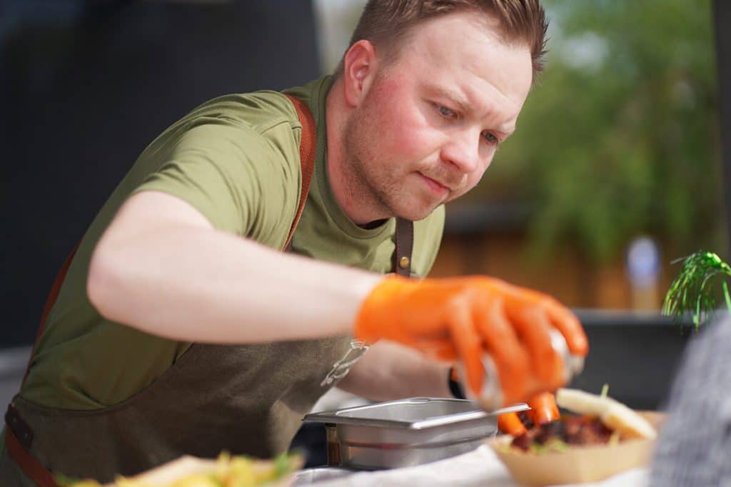 Mann belegt fertigen Burger