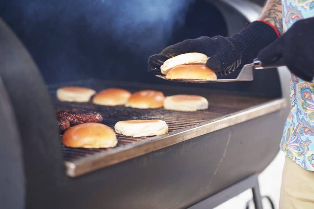 Person bereitet Burgerbrötchen und Fleisch zu