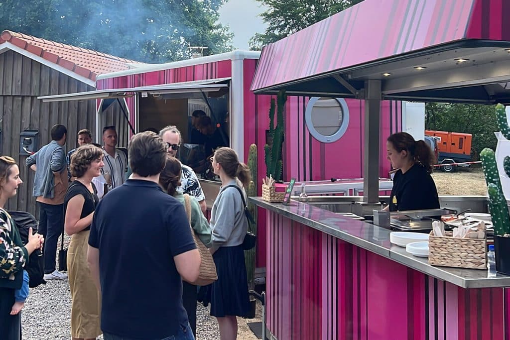 Zwei pinke Foodtrucks stehen Outdoor bei einer Betriebsfeier