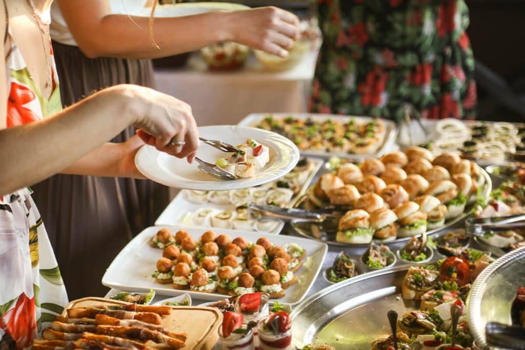 Frau legt sich Essen von einem leckeren Buffet auf den Teller