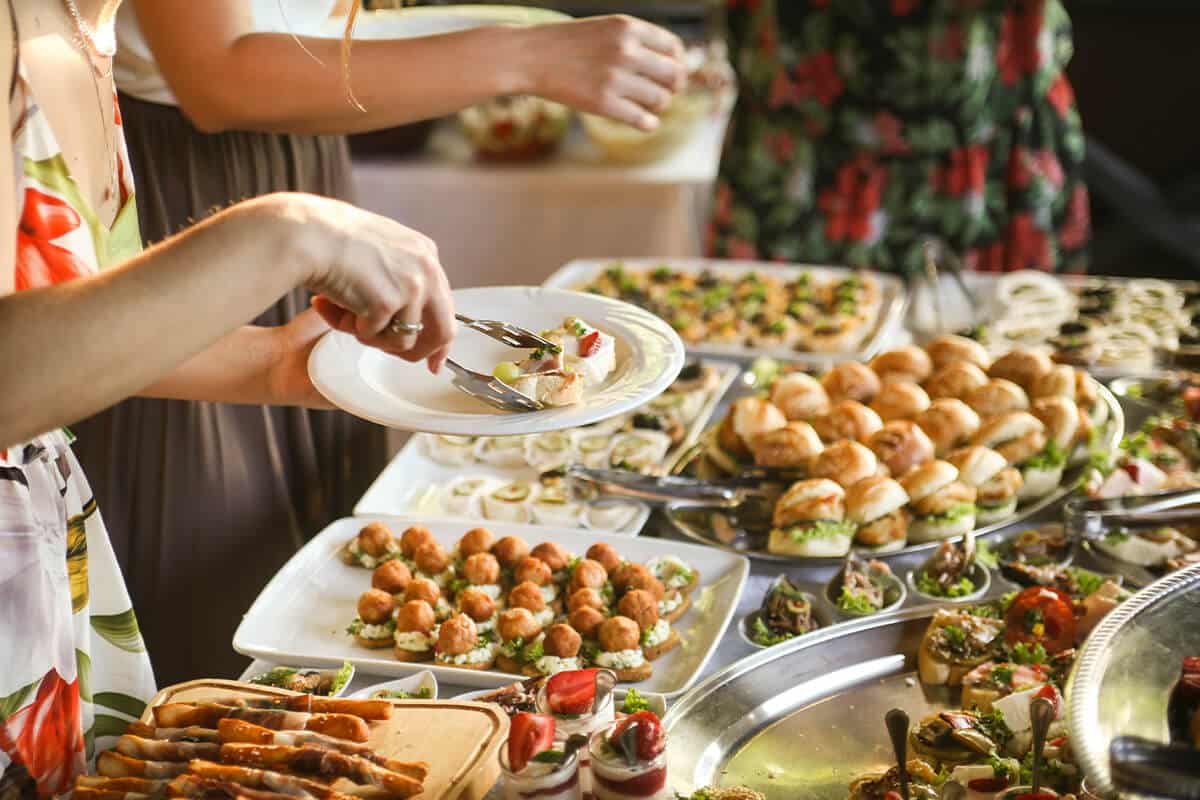 Frau legt sich Essen von einem leckeren Buffet auf den Teller