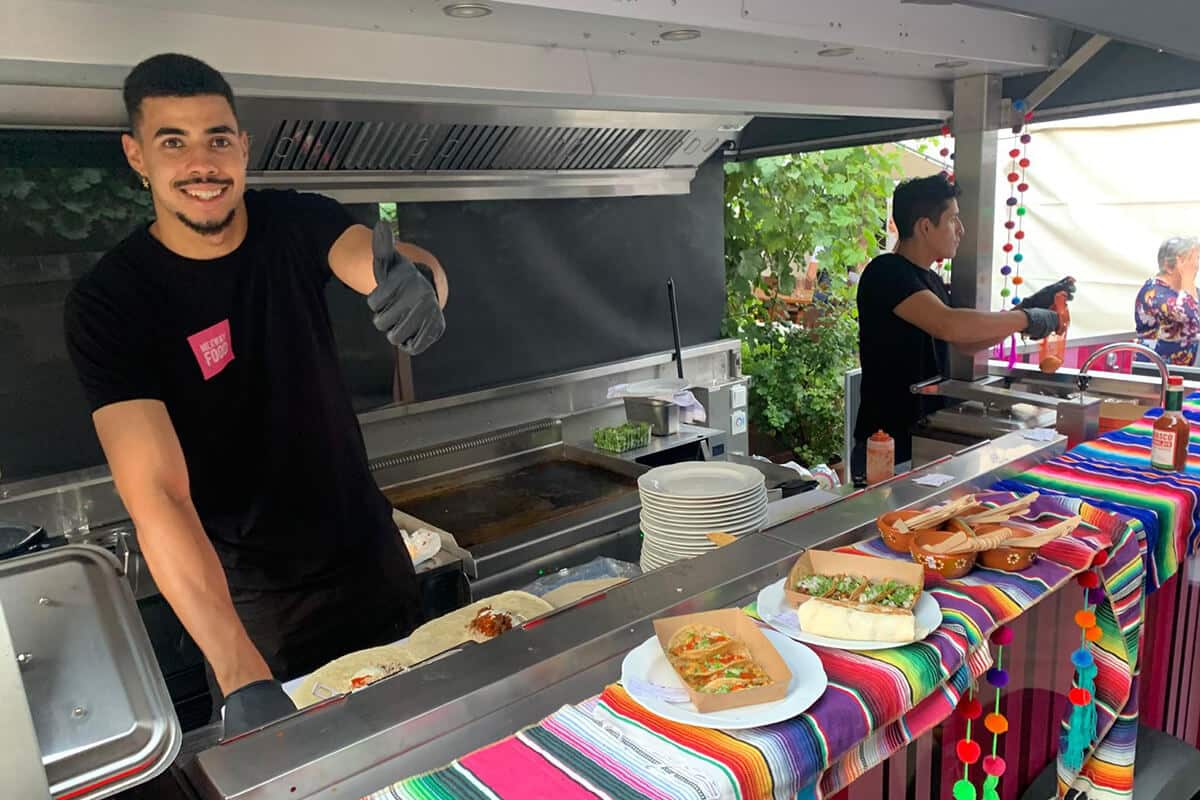 meywayfood Mitarbeiter steht mit ausgestrecktem Daumen nach oben im Foodtruck und bereitet Essen zu