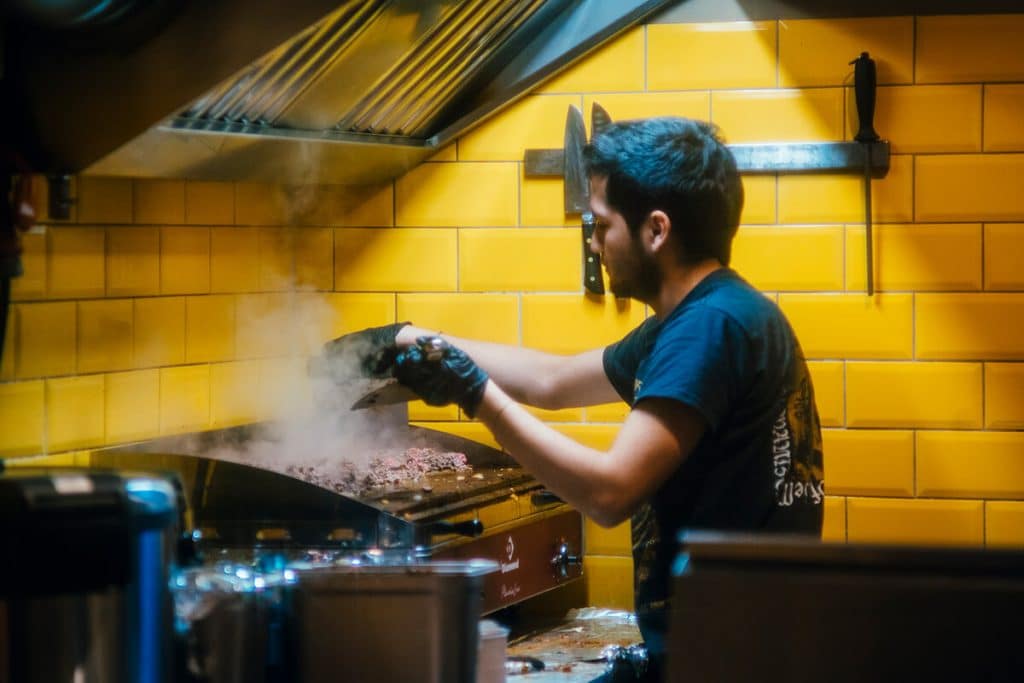 Mitarbeiter am Grill beim Hackfleisch braten